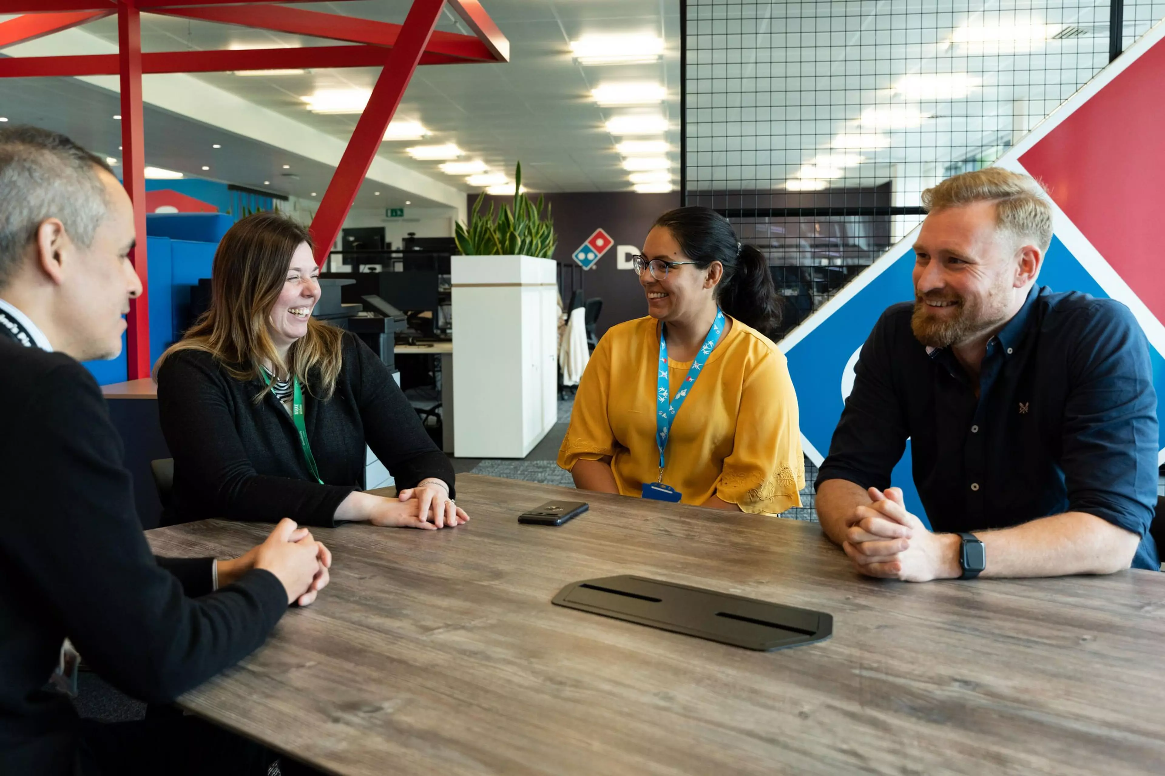 Four people are sat around a table in business casual attire in an office setting.