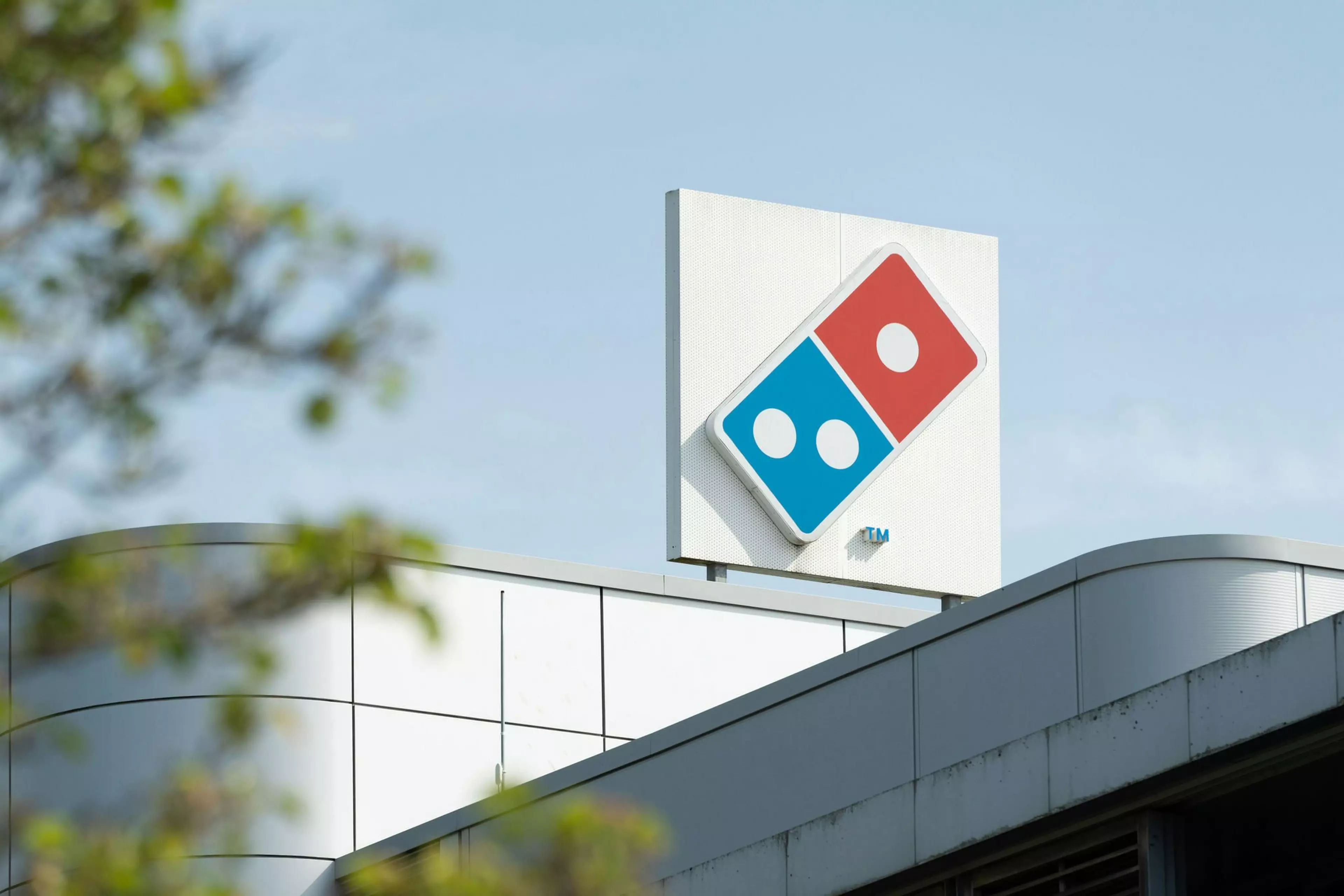 A picture of the Domino's head office, a zoomed in photo of the dominos logo on top of the building.