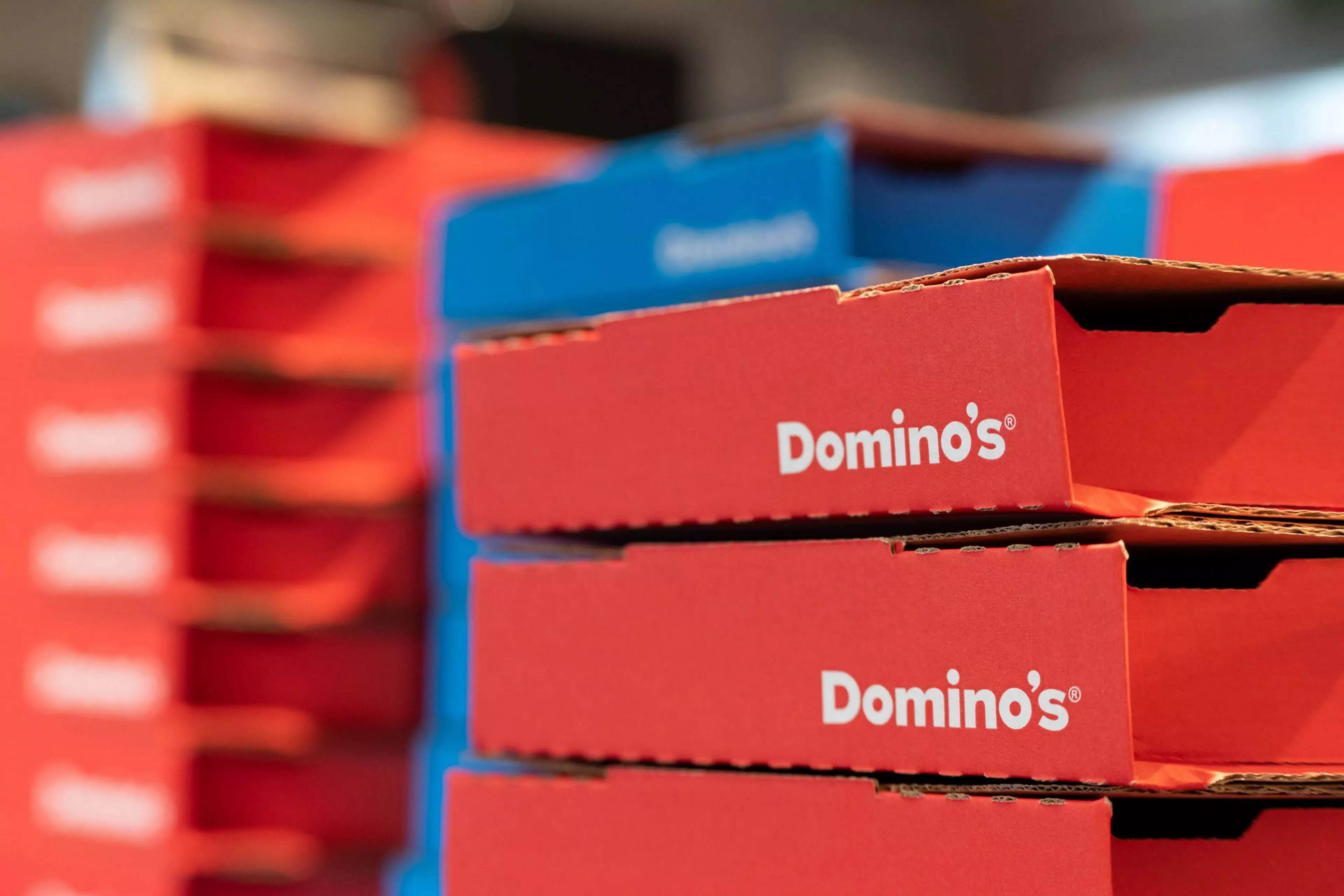 A stack of red and blue Domino's pizza boxes.