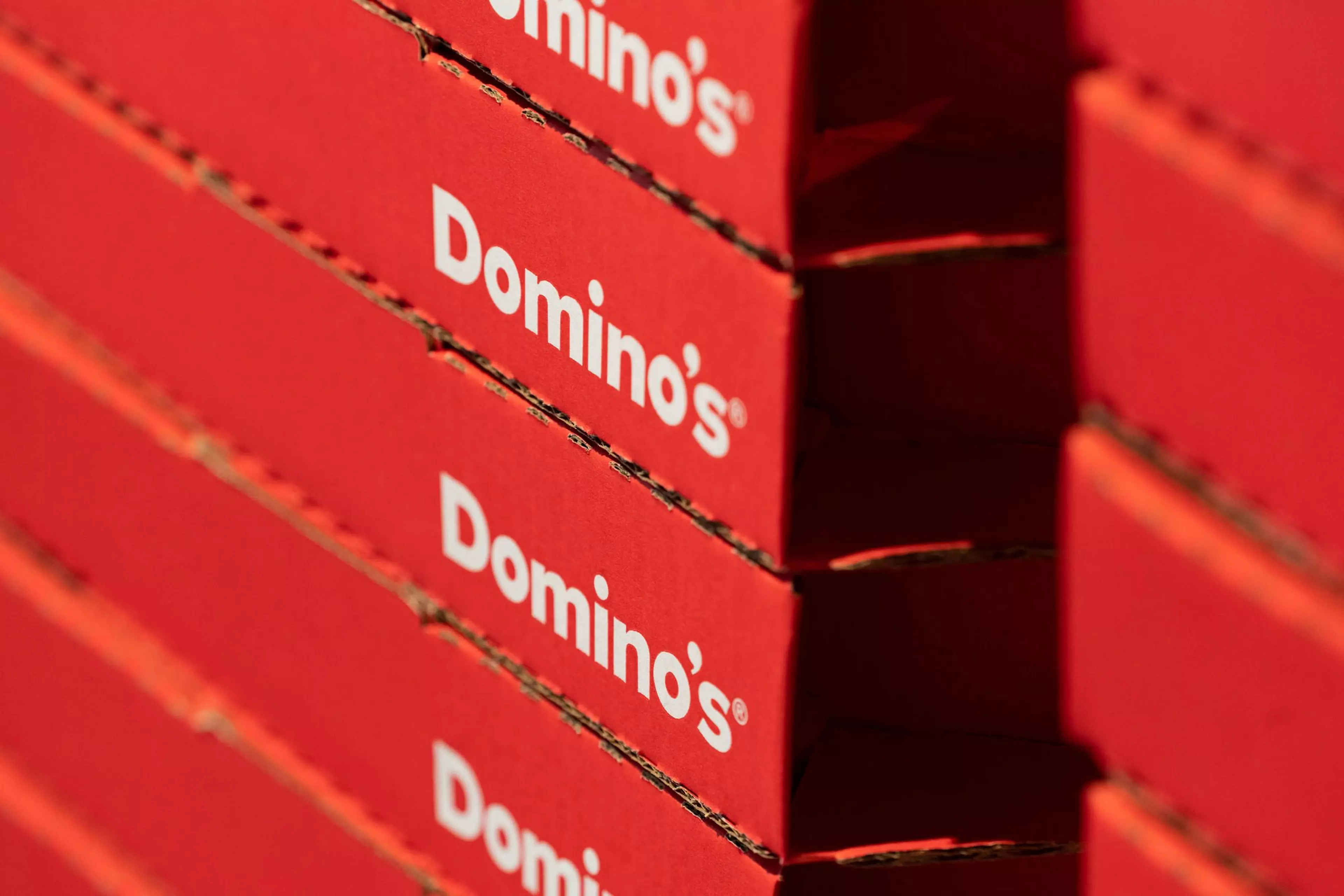 A close up picture of a stack of Domino's pizza boxes.