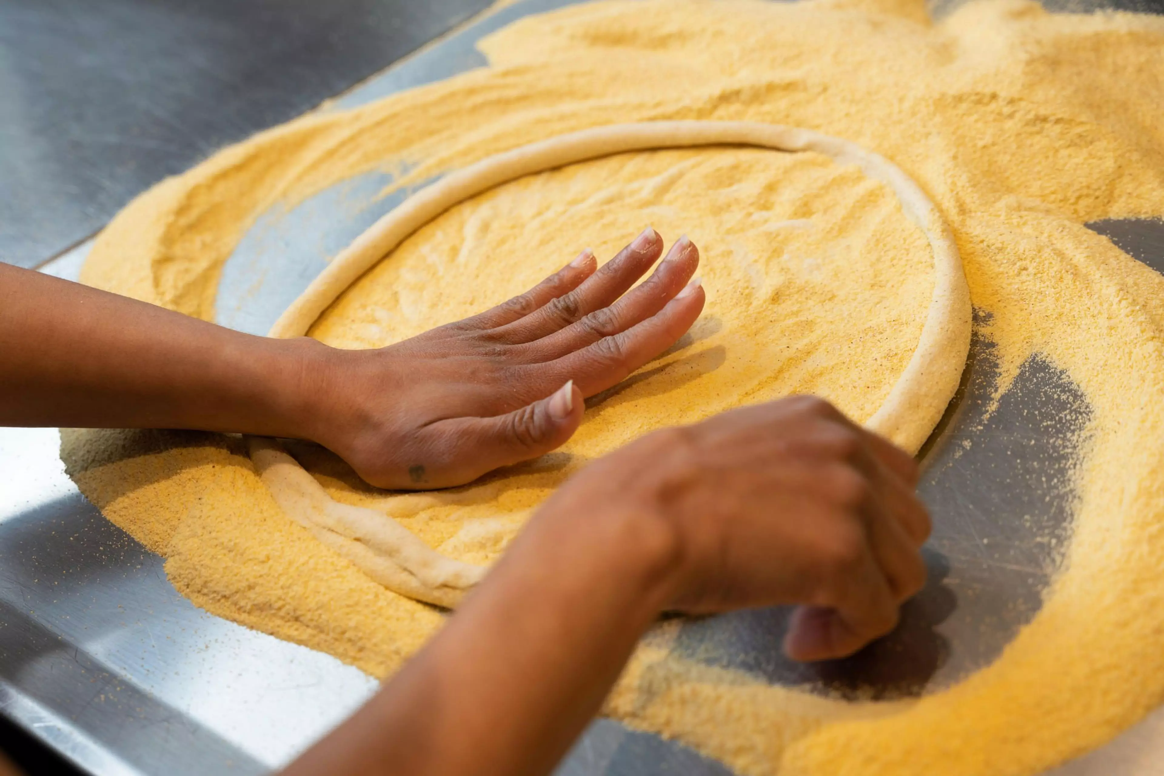 A picture of hands kneading a pizza dough base.