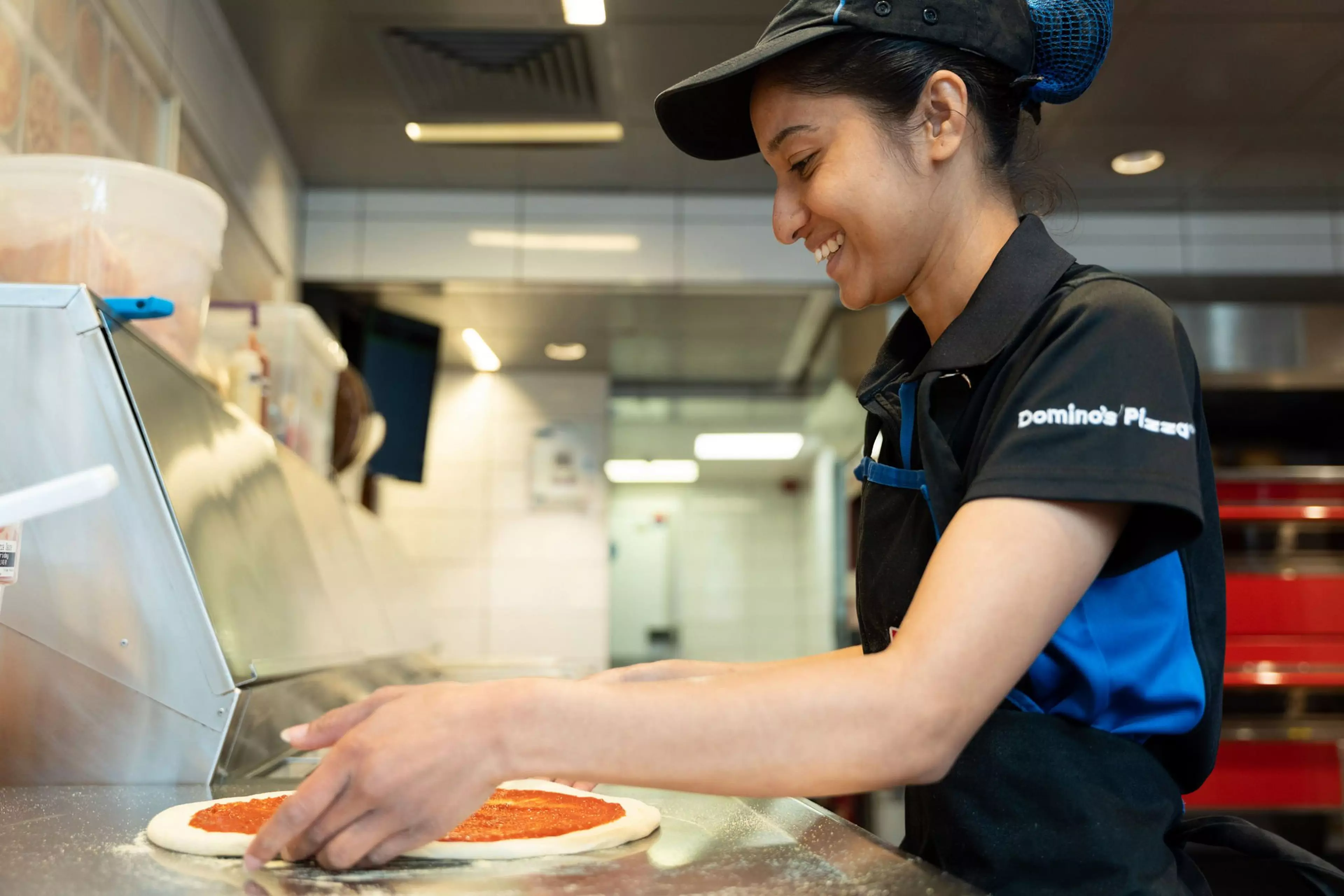 Domino's employee making a pizza, in store