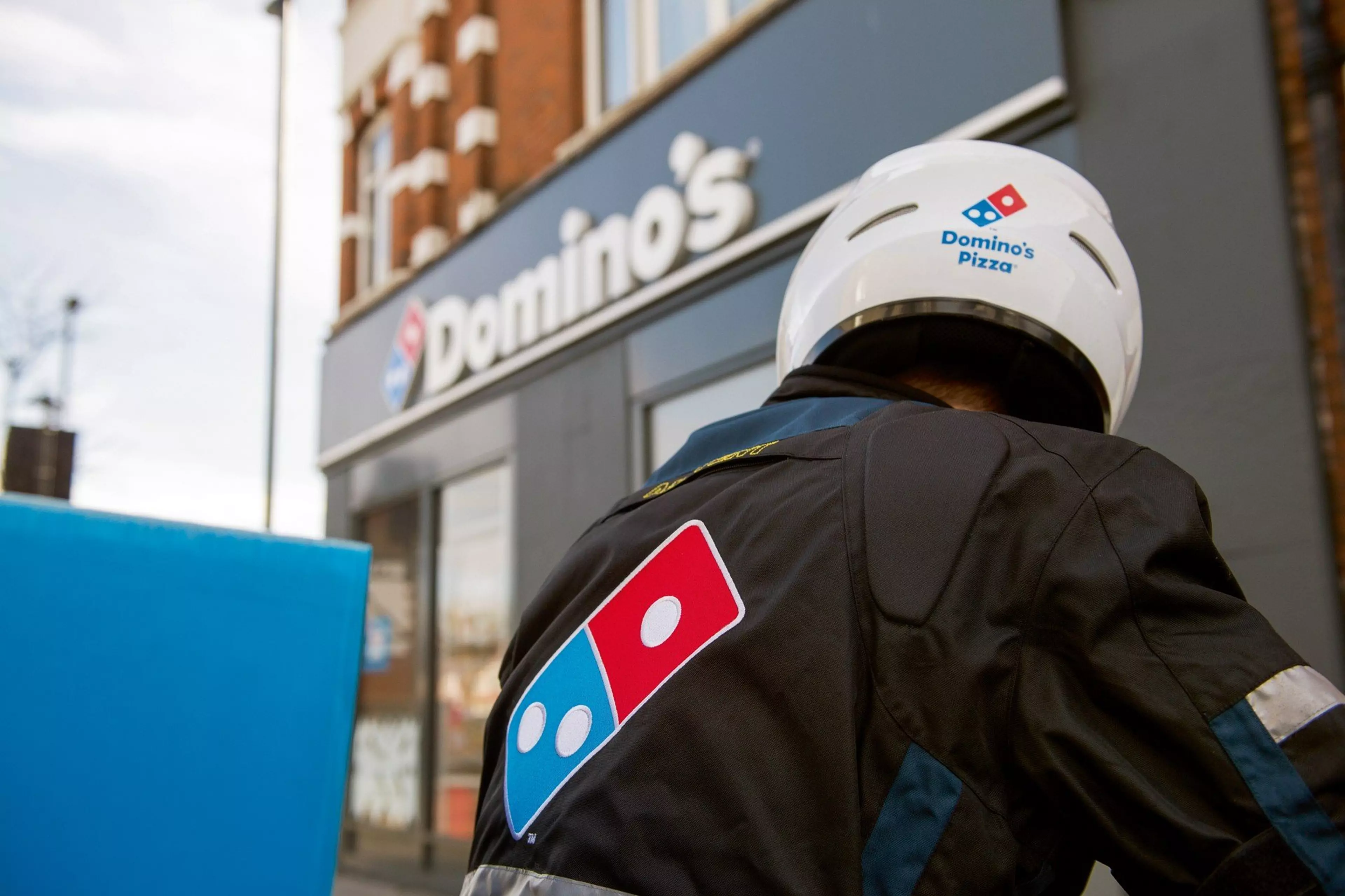 A domino's delivery rider, looking away from the camera