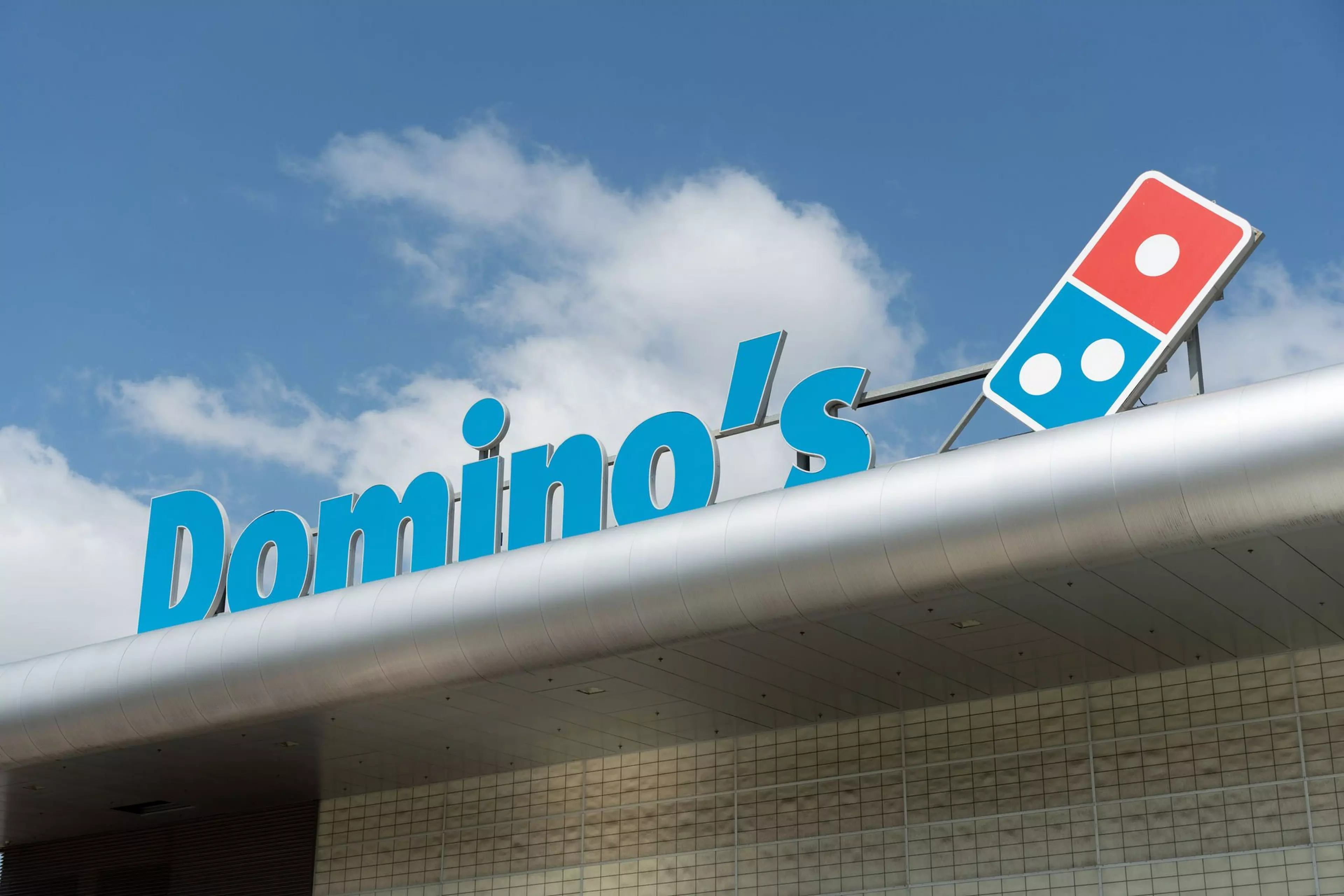 Picture of a Domino's sign on top of a building.