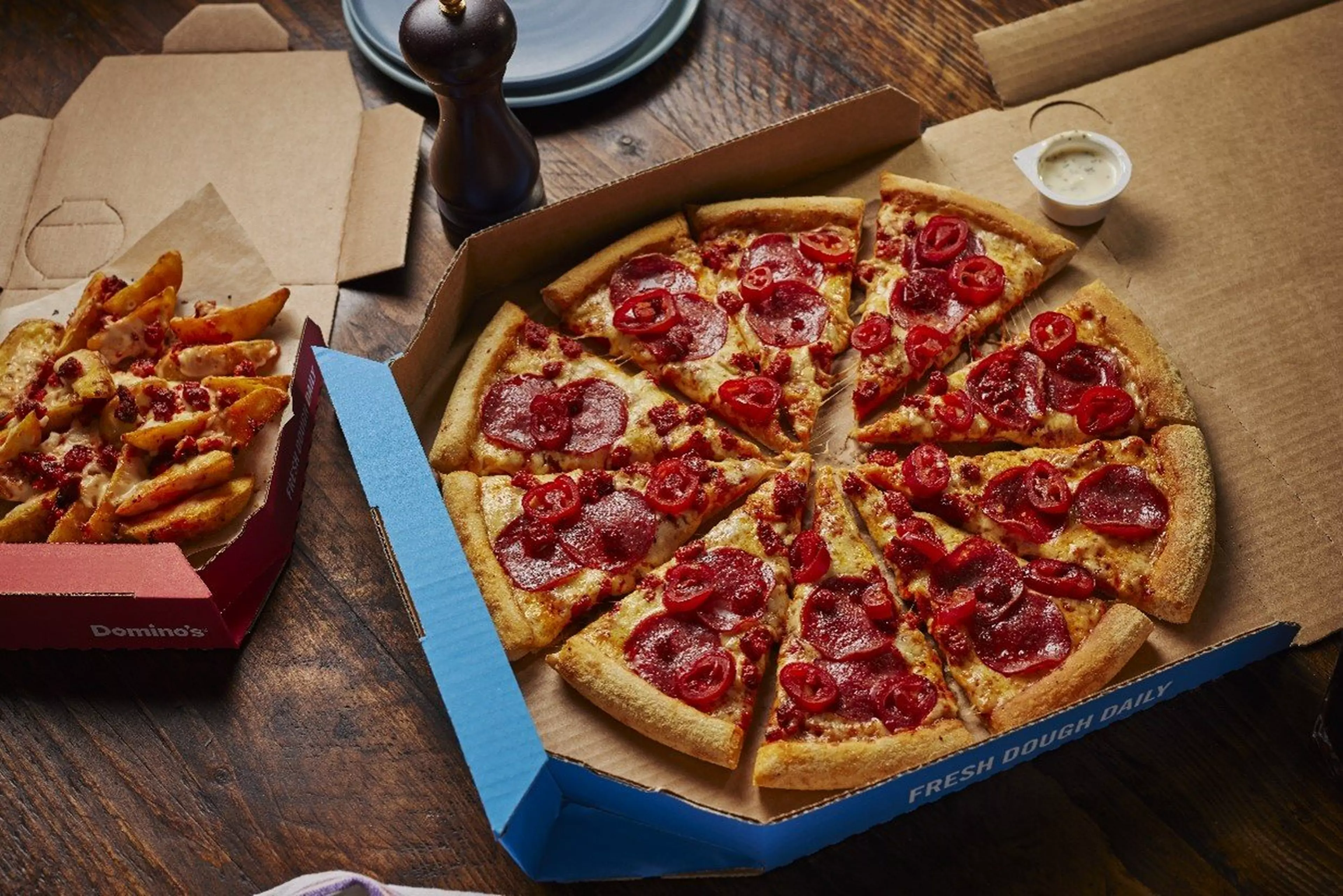 A picture of a domino's pizza in a box next to a box of pizza wedges.